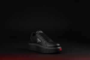 Pair of black sneakers with a brand logo on a dark background