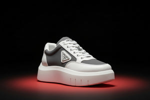 Gray and white sneaker with Prada logo on a white background